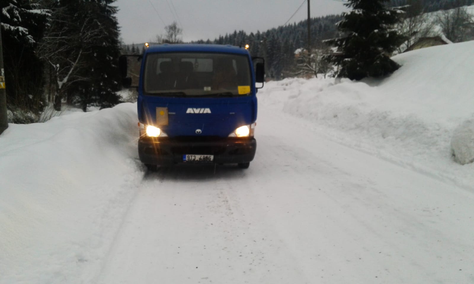 Modrý kontejnerový automobil Avia na zasněžené cestě